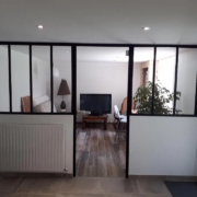 Verrière intérieure à montants noirs séparant un bureau du salon