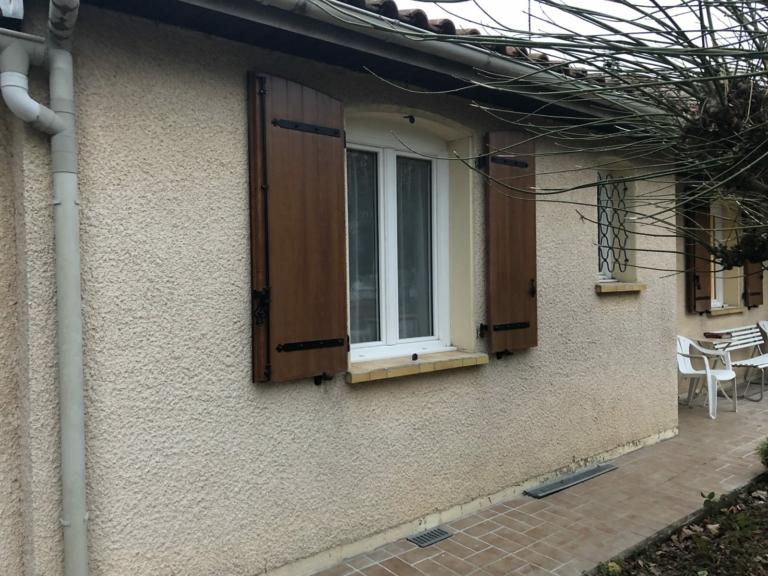 Volets battants aspect bois sur une maison crépie