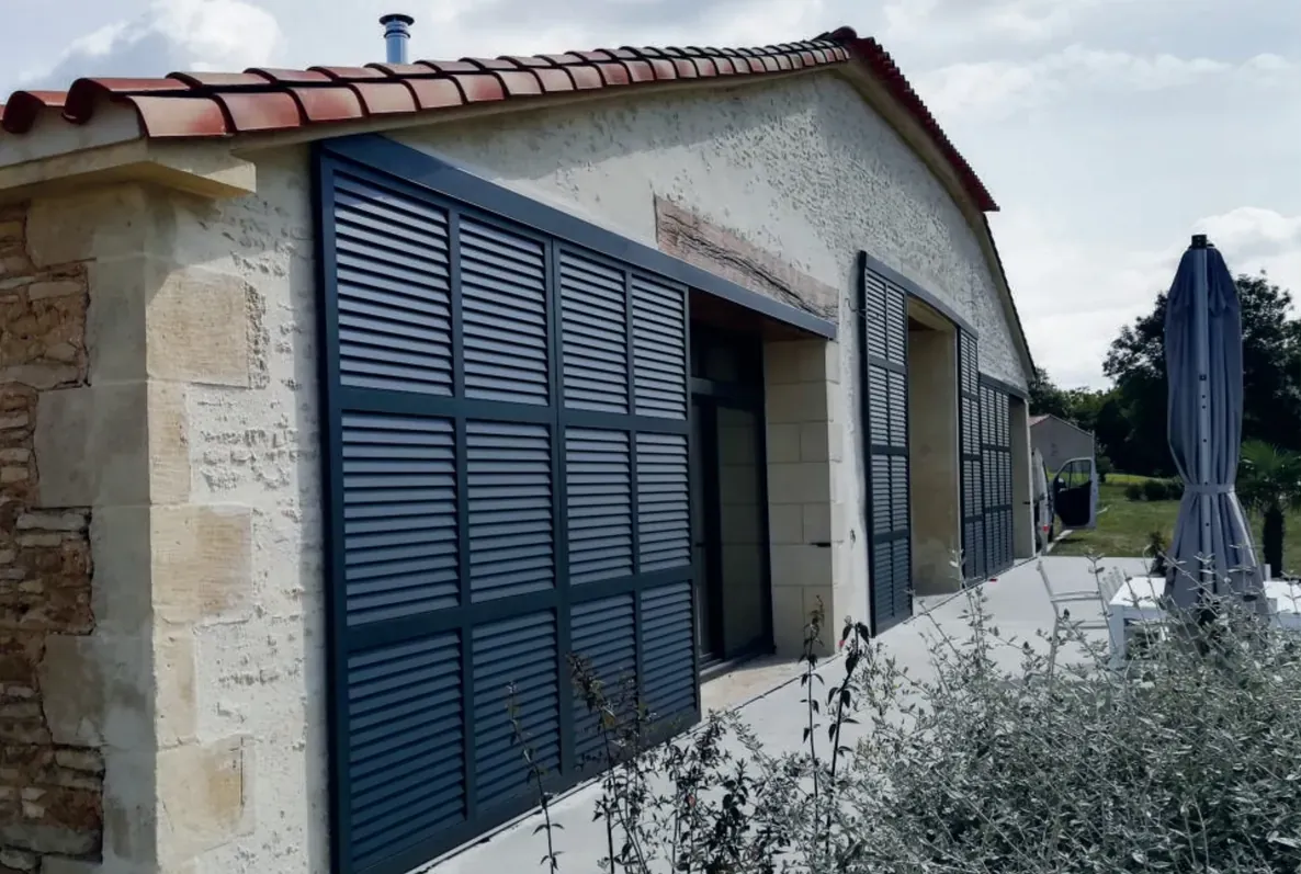 Volets coulissants alu noir sablé sur une longère